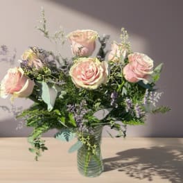 Pink roses arranged in a clear glass vase with airy filler flowers