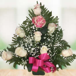 Pink and white roses arranged with baby's breath and a magenta ribbon