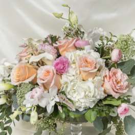 Pastel bouquet of roses, hydrangeas, and white orchids in a glass vase