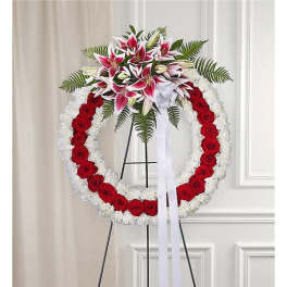 Circular funeral wreath of red roses and white flowers with lilies on a stand