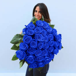 Large bouquet of vivid blue roses held by a woman