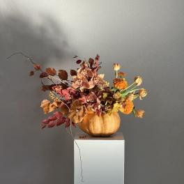 Autumn floral arrangement in a pumpkin vase with orchids and tulips