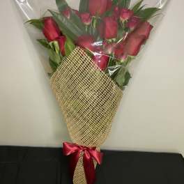 Bouquet of red roses wrapped in clear plastic and burlap with a red ribbon