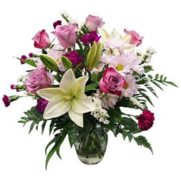 Mixed bouquet of pink roses, lilies, and daisies in a glass vase