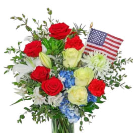 Red and white rose bouquet in a glass vase with an American flag