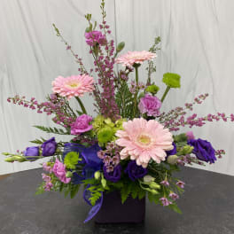 Pink and purple mixed flower arrangement in a dark square vase