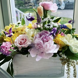 Mixed bouquet in a white rectangular vase with pink, yellow, white, and purple flowers