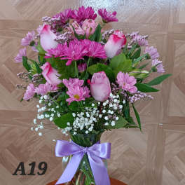 Pink roses and chrysanthemums in a glass vase with a lavender ribbon