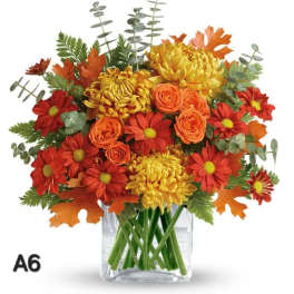 Autumn bouquet of red, orange, and yellow flowers in a clear glass vase