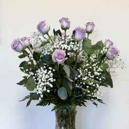 Lavender roses arranged in a clear glass vase with white baby's breath