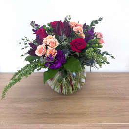 Mixed bouquet of pink and purple roses in a clear glass vase
