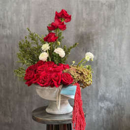 Red roses and white blooms arranged in a pedestal vase