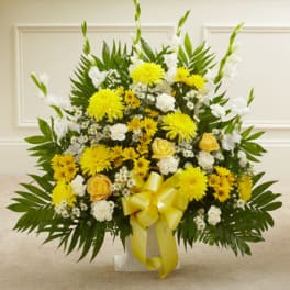 Yellow and white floral arrangement in a vase with a yellow ribbon