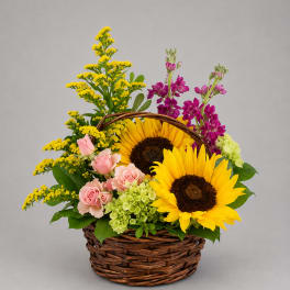 Basket arrangement with sunflowers, pink roses, and purple blooms