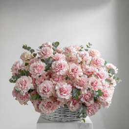 Pink roses in a white wicker basket with eucalyptus accents