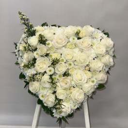 Heart-shaped arrangement of white roses and daisies on an easel