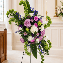 Tall floral spray with purple, white, and green blooms on a stand