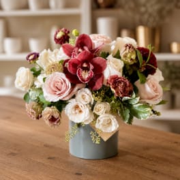 Mixed bouquet of roses and orchids in a gray vase