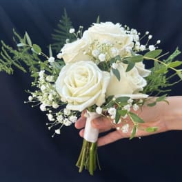 Handheld bouquet of white roses with baby's breath and greenery