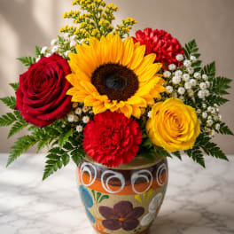 Bouquet with sunflowers, red and yellow roses, and red carnations in a painted vase