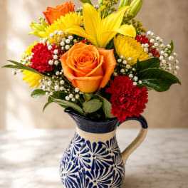 Bouquet of orange and yellow flowers in a patterned ceramic pitcher