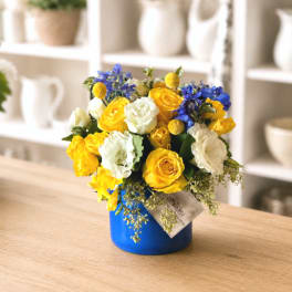 Yellow and white roses with blue flowers in a blue vase