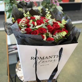 Bouquet of red roses with eucalyptus in a white gift bag