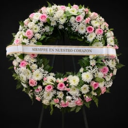 Pink and white floral funeral wreath with a memorial ribbon