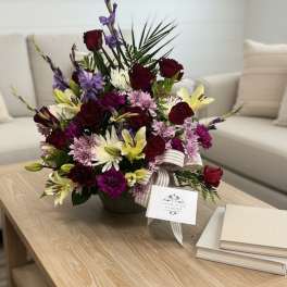 Mixed bouquet in a low vase with roses, lilies, and purple flowers