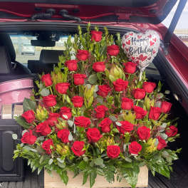 Large bouquet of red roses with a birthday balloon in a car trunk