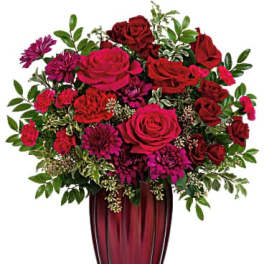 Red and pink roses with purple mums in a tall burgundy vase