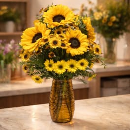 Yellow sunflowers and daisies in an amber glass vase