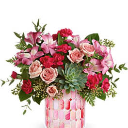 Pink roses and lilies arranged in a patterned glass vase