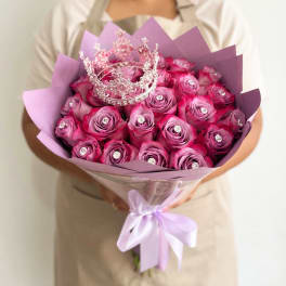 Bouquet of pink roses with a silver crown topper and lavender wrapping