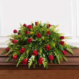 Red roses arranged in a low, full centerpiece with mixed greenery