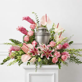Pink floral arrangement with lilies, roses, and an urn centerpiece