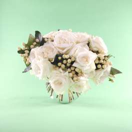 White rose bouquet with berry accents in a small vase