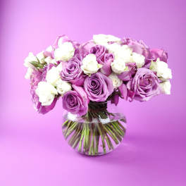 Bouquet of purple and white roses in a clear glass vase