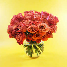 Bouquet of orange and coral roses in a clear glass vase