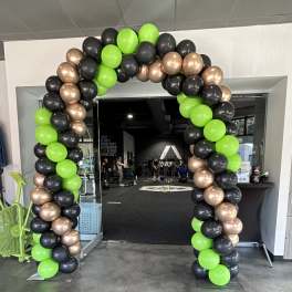 Balloon arch in neon green, black, and metallic gold at a gym entrance.