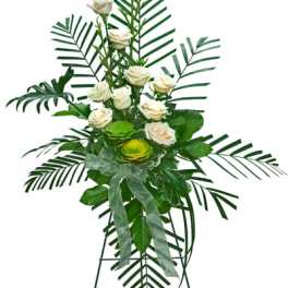Tall standing spray of white roses with large palm fronds and green accents on an easel