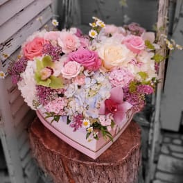 Heart-shaped box filled with pink and white roses and mixed flowers