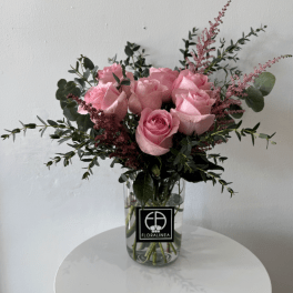 Pink roses in a clear glass vase with airy greenery