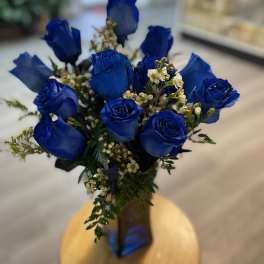 Bouquet of blue roses with small white filler flowers in a vase
