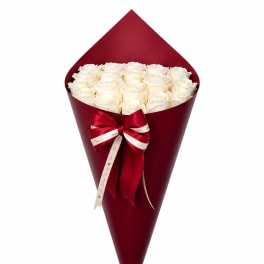 Bouquet of white roses wrapped in deep red paper with a ribbon