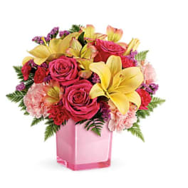 Bouquet of pink roses, yellow lilies, and carnations in a pink vase