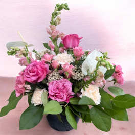 Pink and white mixed flower arrangement in a dark vase