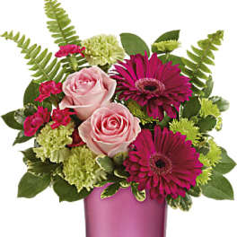 Pink roses and magenta gerberas in a pink glass vase
