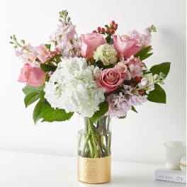 Pink and white bouquet in a clear glass vase with a gold base