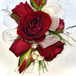 Red rose corsage with white ribbon and small white accents